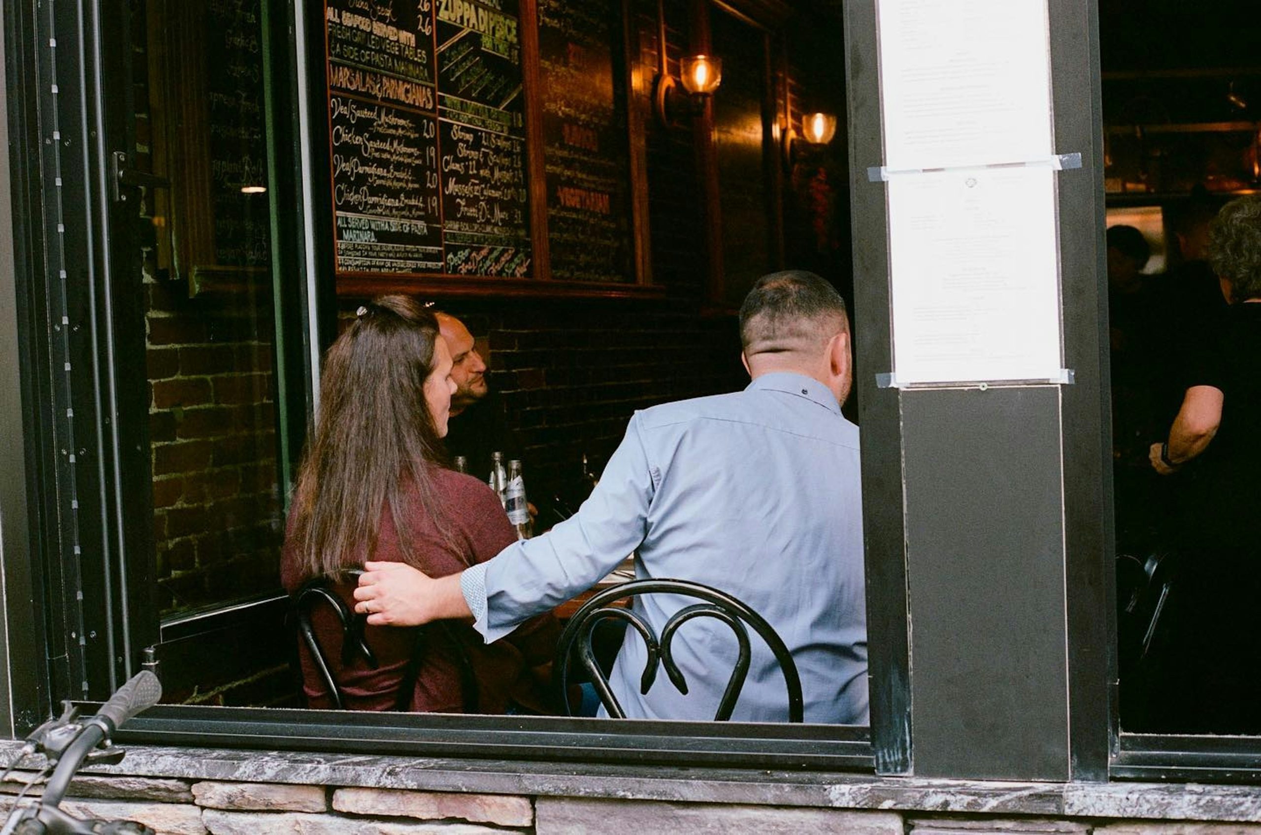 People seated at a restaurant table with limited mobility and close-quarters conditions, highlighting the challenges of drawing from concealment while seated.