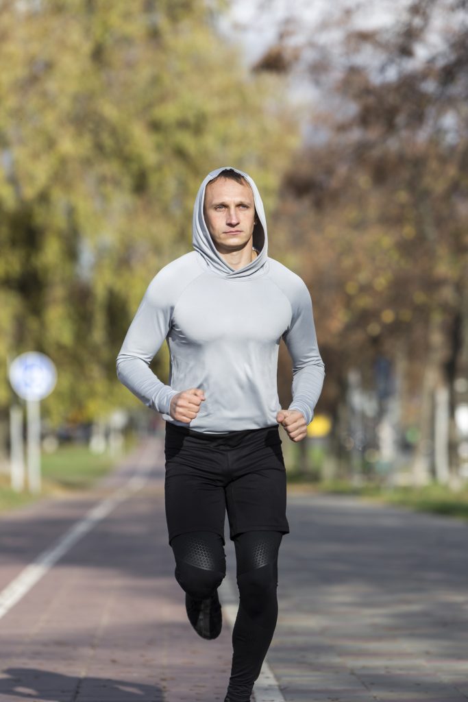 A person jogs outdoors in athletic gear, representing concealed carry and fitness challenges like running with a secure setup using Clipdraw gun clips.